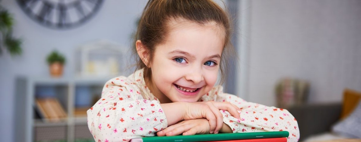 Fetita vesela zambind intr-o sala de clasa in timp ce sta la birou