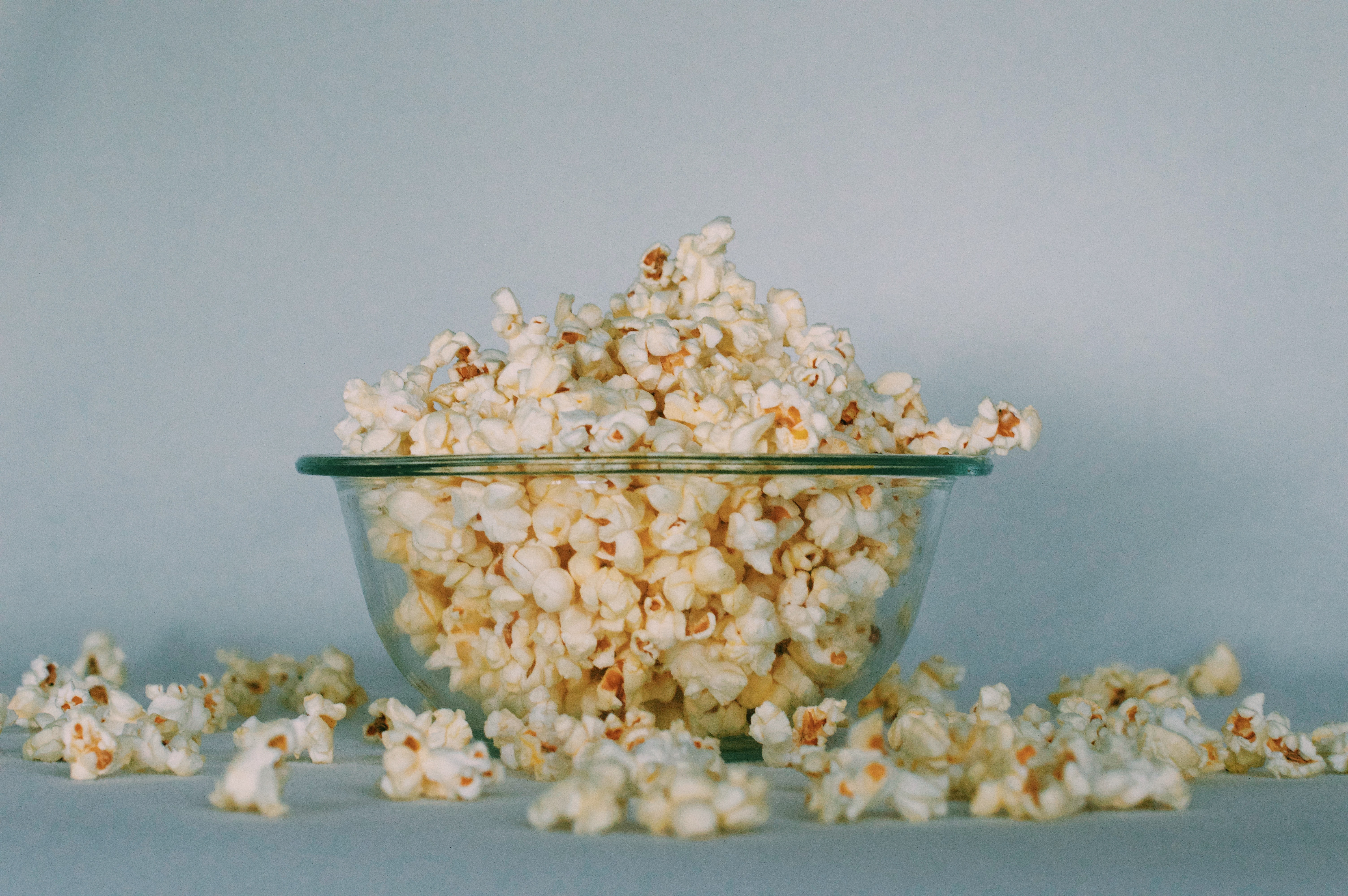 Castron de popcorn pe o masa de sticla care sa fie mancat in timp ce vizionezi un film in limba engleza