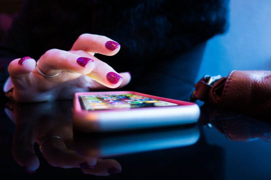 mana de femeie ce se pregateste sa tasteze ceva pe un telefon cu aplicatii instalate pentru a invata engleza