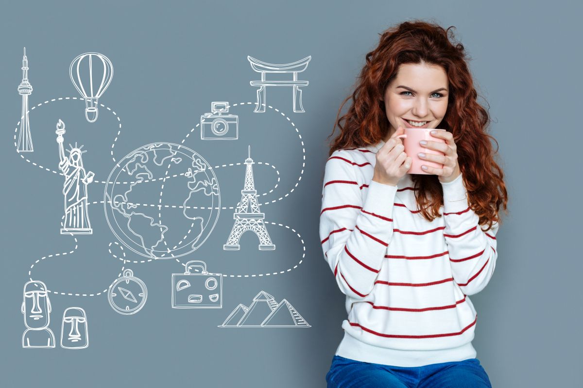 Femeie roscata cu par lung ondulat si pulover alb cu dungi rosii savureaza o ceasca de cafea zambind iar pe fundalul albastru sunt proiectate cu alb simboluri desenate interconectate ale diverselor tari in care se vorbeste engleza