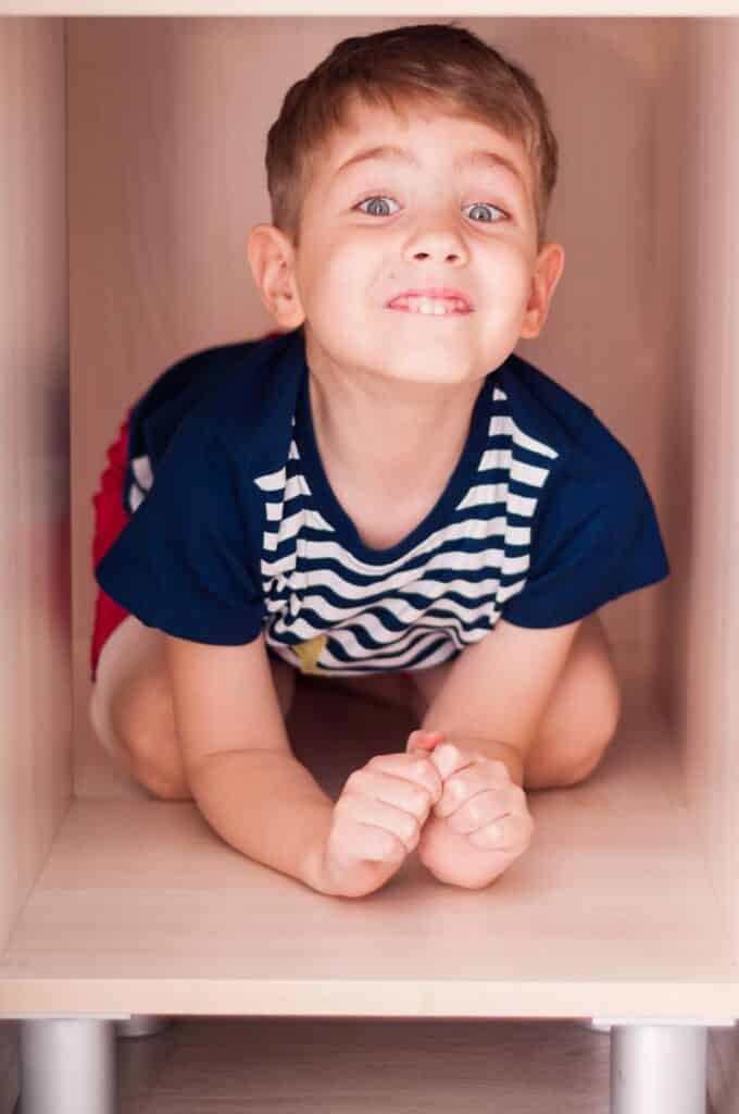 baietel se joaca si zambeste intr-un dulap