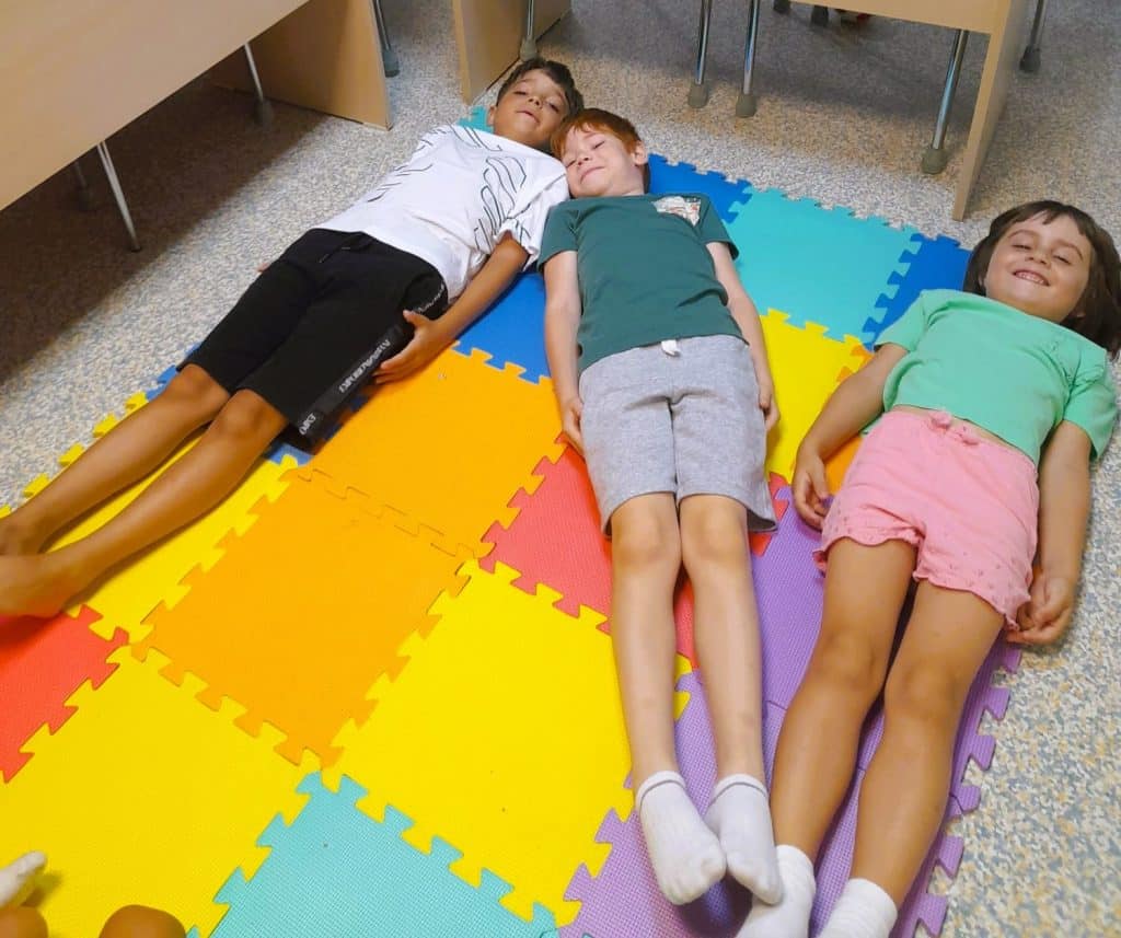 trei copii alcatuiesc cu corpurile lor pe podea litera N