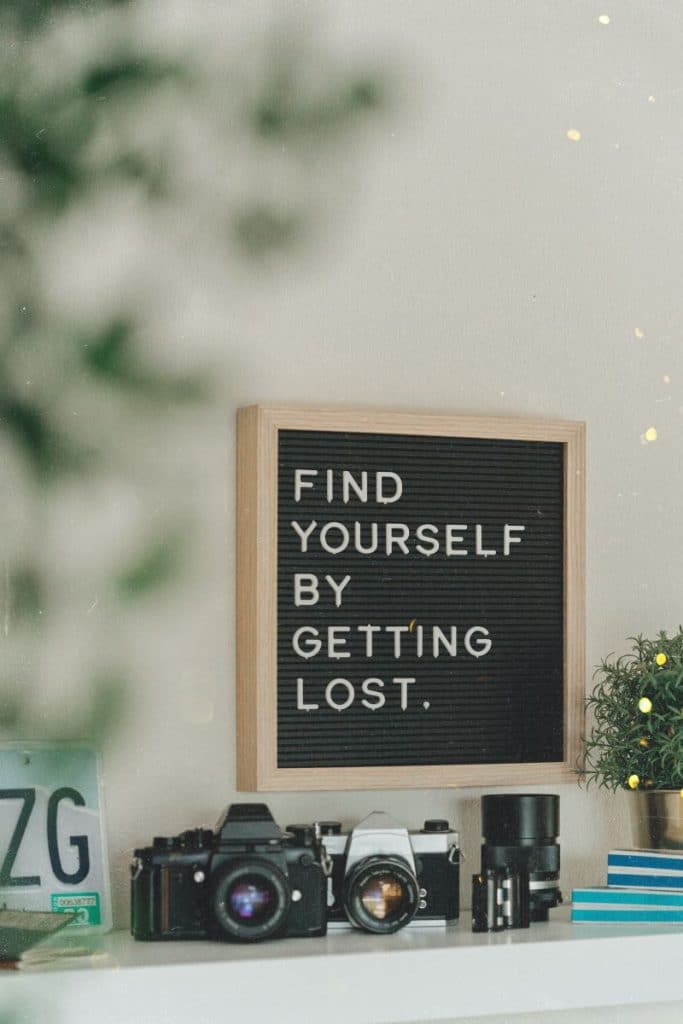 Citat motivational in engleza scris pe o tabla neagra deasupra unui birou alb pe care se afla mai multe aparate de fotografiat