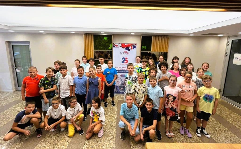 grupa de copii zambitori care au sustinut examenul cambridge si acum sunt in fata salii de examinare