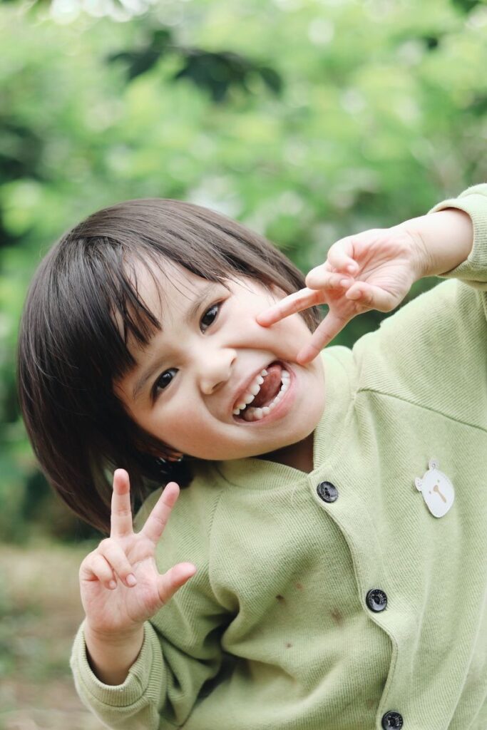 fetita de varsta prescolara bruneta cu par mediu imbracata in lovar verde entuziasta ca invata engleza rade si arata degetelele