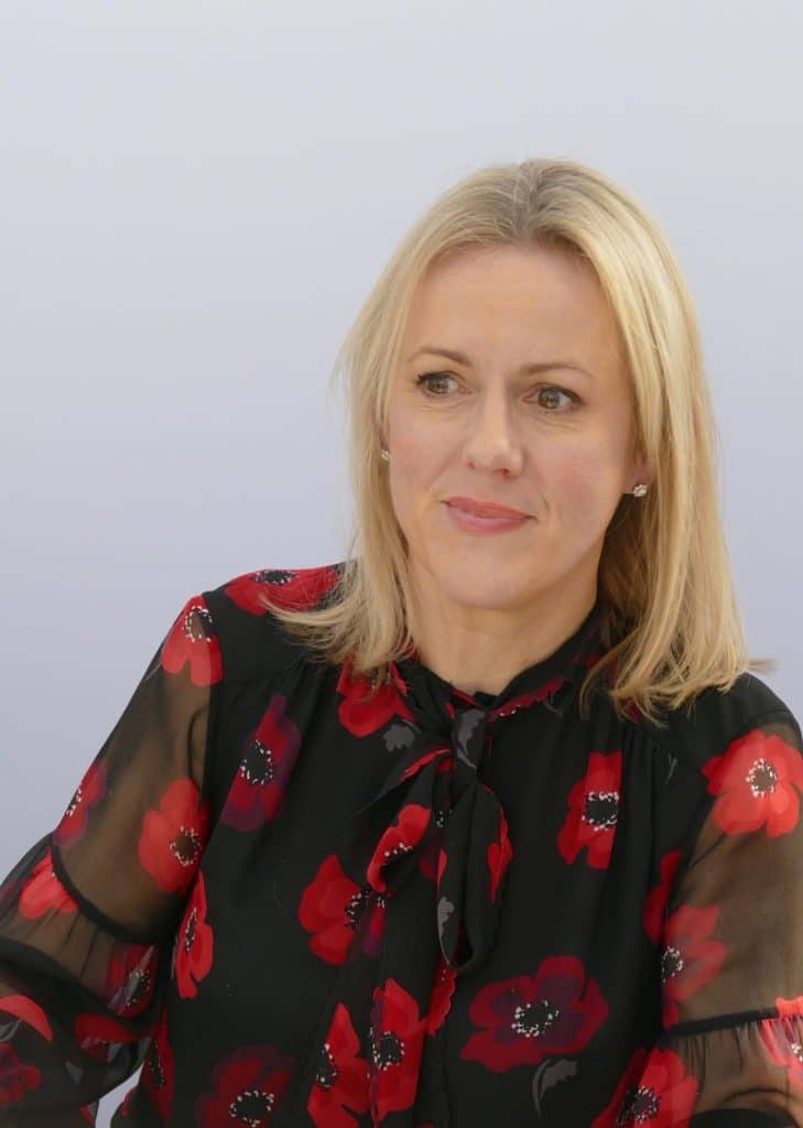 autoarea britanica Jojo Moyes zambitoare imbracata cu bluza negru cu rosu