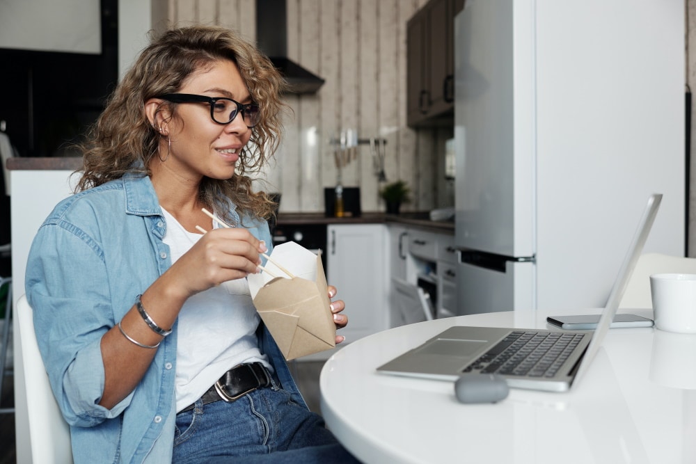 Tanara care mananca si se uita la film in engleza, fara subtitrare, pe laptop